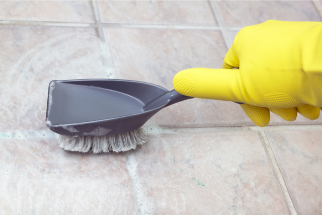 Worker Cleaning Tiles with a special brush and yellow gloves on.